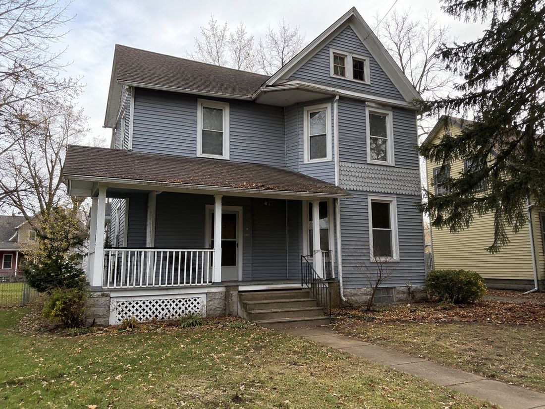 A two-story farmhouse with a wraparound porch
